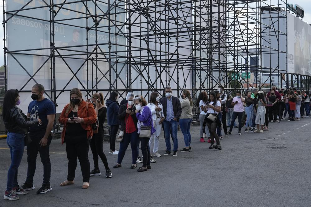 ARCHIVO - Gente hace fila para un concierto del cantante mexicano Alejandro Fernández y la cantante colombiana Jessi Uribe el 3 de marzo de 2022 en Caracas.  Después de años, grandes estrellas están volviendo a incluir en sus giras a Venezuela, donde los boletos pueden costar entre 55 y 600 dólares.  (Foto AP/Ariana Cubillos, archivo)