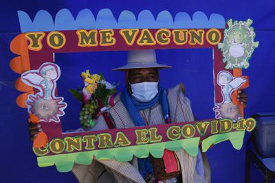Un residente sostiene un marco con un mensaje mientras posa para una foto durante una campaña de vacunación dirigida a la comunidad indígena Uru Chipaya, en Chipaya, Bolivia, el viernes 23 de julio de 2021. (AP Foto/Juan Karita)