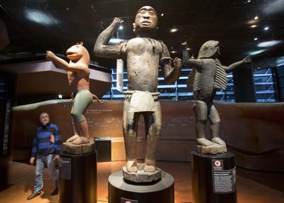 En esta imagen del viernes 23 de noviembre de 2018, un visitante mira estatuas de madera del reino de Dahomey, elaboradas en el siglo XIX en el museo de Quai Branly en París, Francia. En una decisión con posibles consecuencias en museos de toda Europa, Francia mostraba por última vez 26 objetos expoliados en la era colonial antes de enviarlos de vuelta a Benín. (AP foto/Michel Euler, Archivoe)