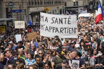 Manifestantes antivacunas desfilen en París para protestar contra las medidas más recientes del gobierno francés para combatir el incremento de infecciones con coronavirus.  (AP Foto/Michel Euler)