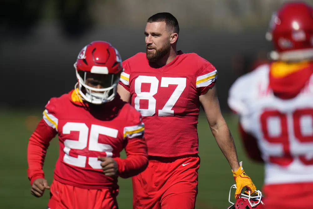 Kansas City Chiefs running back Clyde Edwards-Helaire (25), tight end Travis Kelce (87) and defensive tackle Khalen Saunders (99) pause on the field after warming up during an NFL football practice in Tempe, Ariz., Thursday, Feb. 9, 2023. The Chiefs are scheduled to play against the Philadelphia Eagles in Super Bowl LVII on Sunday. (AP Photo/Ross D. Franklin)