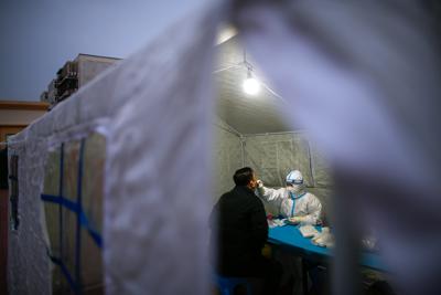 Un operario, con un traje de protección, toma una muestra para una prueba de detección del coronavirus, en Tianjin, en el norte de China, el 20 de enero de 2022. (Chinatopix vía AP)