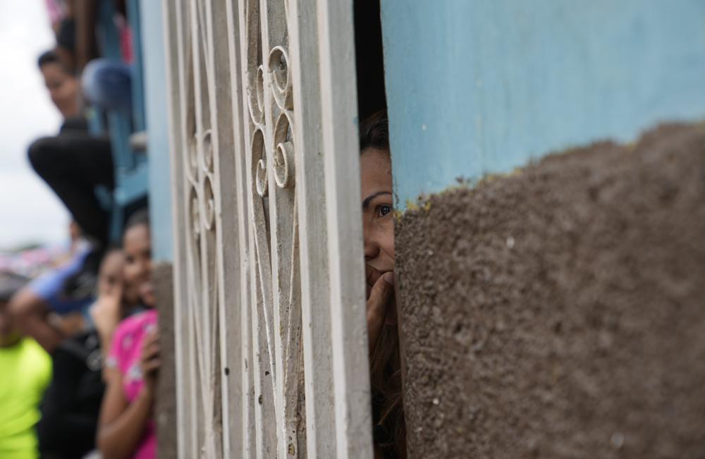 A woman looks through a window during an event for kids at a soup kitchen in the neighborhood of Antimano in Caracas, Venezuela,Tuesday, July 27, 2021. The soup kitchen was celebrating a belated national children's a day with different cultural activities, amid the new coronavirus pandemic. (AP Photo/Ariana Cubillos)