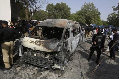 Investigadores paquistaníes examinan los restos calcinados de una furgoneta en el sitio de un ataque suicida en Karachi, Pakistán, el 26 de abril del 2022. El ataque mató a cuatro personas, incluyendo tres ciudadanos chinos.  (AP Foto/Fareed Khan)