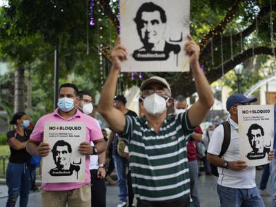 La gente sostiene carteles con la imagen del empresario Alex Saab, quien ha sido extraditado a Estados Unidos, durante una manifestación exigiendo su liberación en Caracas, Venezuela, el domingo 17 de octubre de 2021. Saab, a quien Estados Unidos señala como presunto testaferro del presidente venezolano Nicolás Maduro, comparecipo el lunes 18 de ocrtubre de 2021 ante un tribunal federal de Miami para ser notificado formalmente de ocho acusaciones de lavado. (AP Foto/Ariana Cubillos)