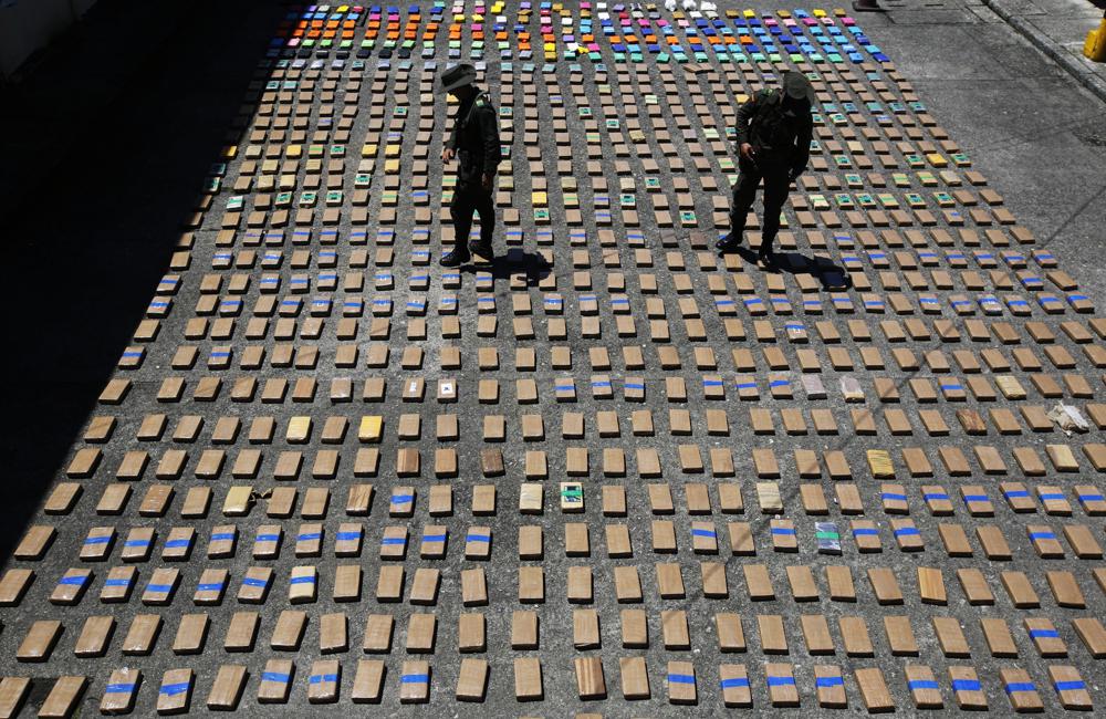 FILE - In this Thursday, Aug. 10, 2017 file photo, police officers walk among packages of seized cocaine at the Pacific port of Buenaventura, Colombia, after about one ton of cocaine was seized in a container during an operation by counternarcotics police at the port. In 2018, Capt. Juan Pablo Mosquera, a Colombian national police officer who was part of an elite unit that worked closely with U.S. anti-narcotics agents, was extradited to Miami to stand trial on charges he betrayed the U.S. Drug Enforcement Administration to the same traffickers they were jointly fighting. (AP Photo/Fernando Vergara)