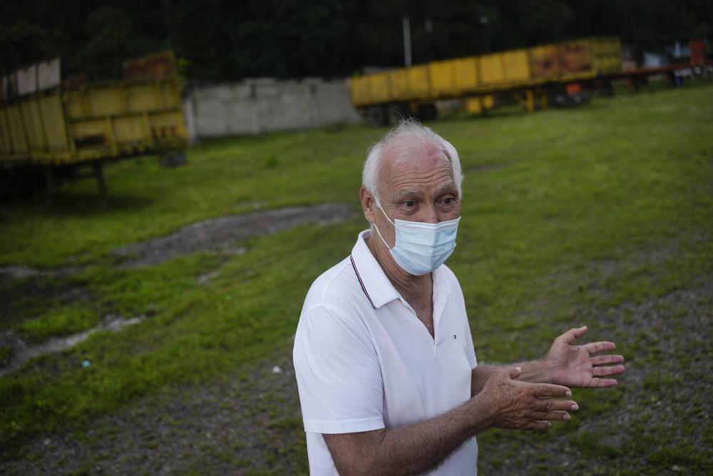 Alfredo Rosales talks with an AP reporter on his property in San Juan de Colon, Venezuela, Thursday, Aug. 4, 2022, on the Colombian border. Rosales said he had a prosperous fleet of over 50 trucks before the border was partially closed by the Venezuelan government in 2015, but had to downsize to four trucks and sell the rest as scrap as the Colombian coal import business dropped. (AP Photo/Matias Delacroix)