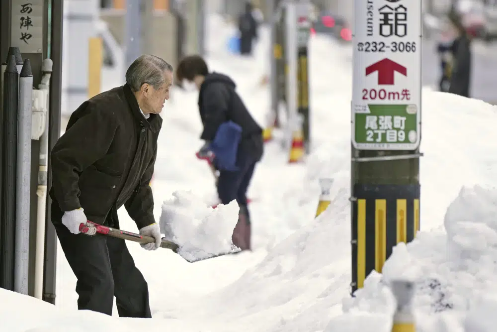 Residents shovel snow off a sidewalk in Kanazawa, Ishikawa prefecture, central Japan, on Dec. 24, 2022. (Kyodo News via AP)