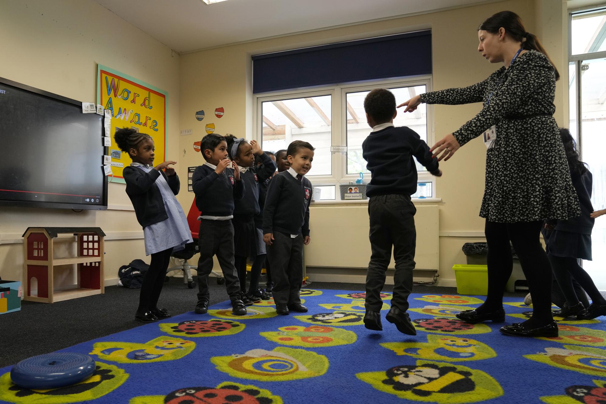 Amariah, left, with Anay, Mathew and Nevaeh, take part in a lesson with reception class teacher Becky Slight, at the Holy Family Catholic Primary School in Greenwich, London, Thursday, May 20, 2021. (AP Photo/Alastair Grant)