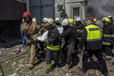 Bomberos trasladan un cuerpo que sacaron que entre los escombros de un edificio residencial alcanzado por un ataque ruso, en Uman, en el centro de Ucrania, el 28 de abril de 2023. (AP Foto/Bernat Armangué)