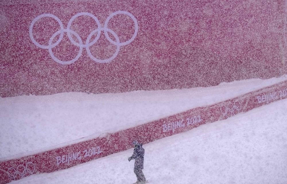 A course worker stands in the finish area of the men's giant slalom course as the snow comes down at the alpine ski venue at the 2022 Winter Olympics, Sunday, Feb. 13, 2022, in the Yanqing district of Beijing. (AP Photo/Luca Bruno)