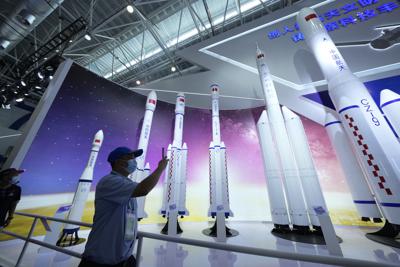 ARCHIVO - En esta imagen del 29 de septiembre de 2021, un visitante toma fotos de réplicas de cohetes espaciales de lanzamiento en la Feria Aérea China de 2021 en Zhuhai, en la provincia sureña china de Guangdong. (AP Foto/Ng Han Guan, Archivo)