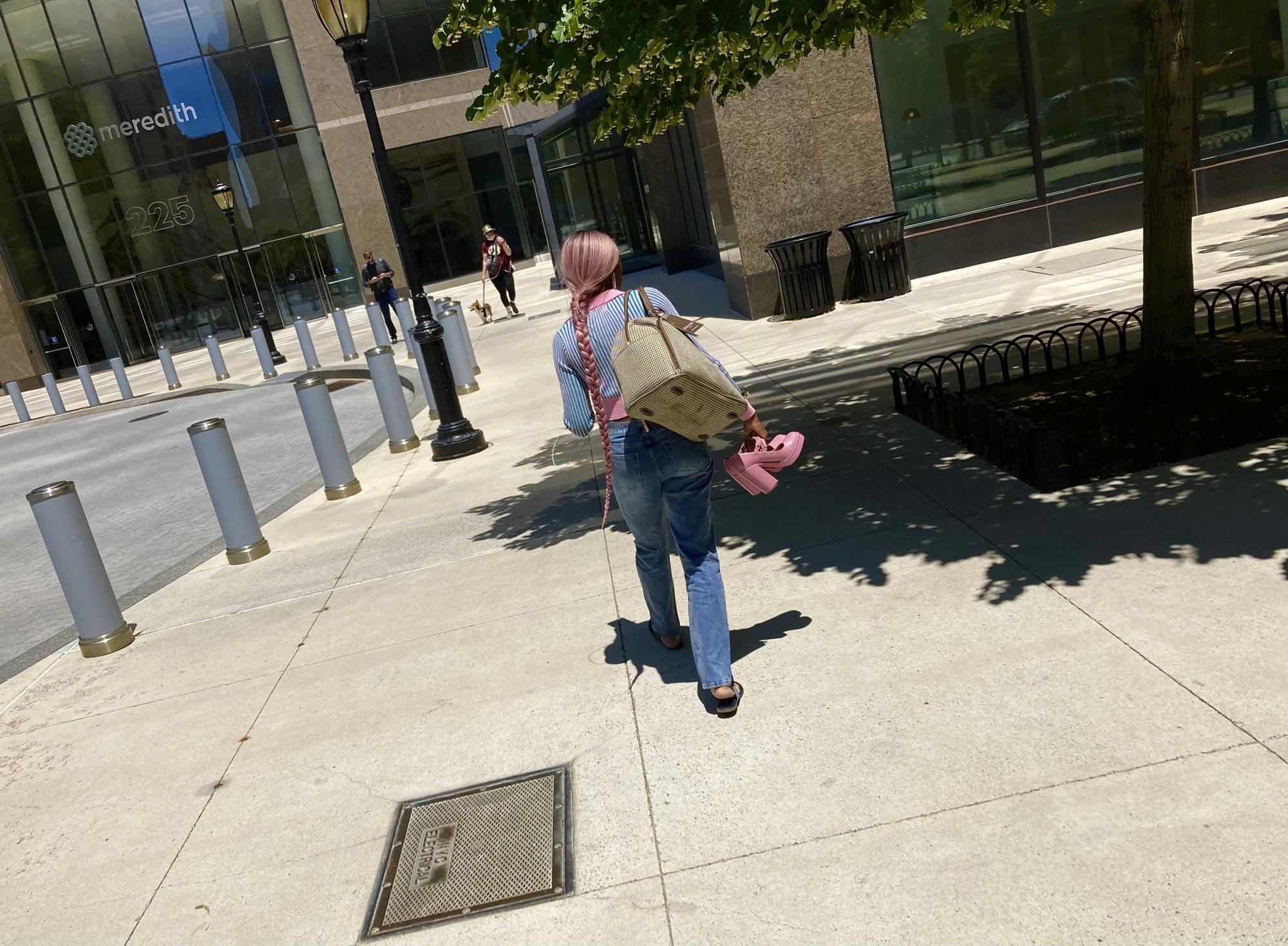 CORRECTS YEAR TO 2022 - A woman carrying a pair of pink shoes walks near the Sept. 11 memorial in New York in this Monday, June 6, 2022 iPhone photo. "Sometimes I feel that photography has almost lost the magic thing that it had before the means to take a photo and share it with the world was in our pocket," wrote Marti. (AP photo/Enric Marti)