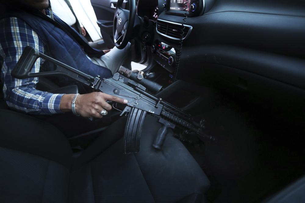 Un guardaespaldas asignado por el gobierno para proteger a Guillermo Valencia, candidato a la alcaldía de Morelia por el PRI, sostiene su fusil de asalto el sábado 22 de mayo de 2021 durante una de las escalas de campaña del candidato en esa ciudad del estado de Michoacán, México. (AP Foto/Marco Ugarte)