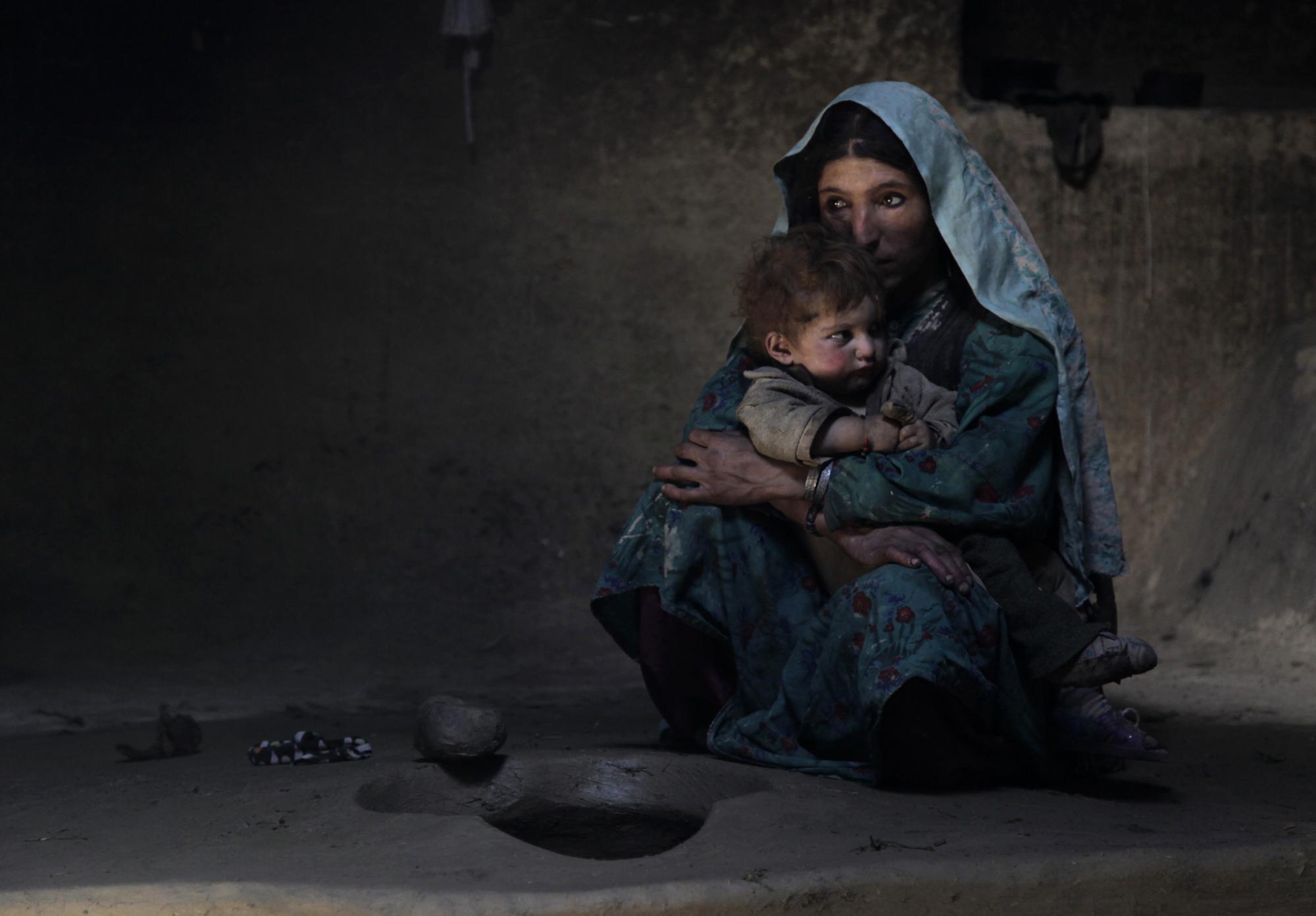 Sarab village resident Raihan comforts her 1-year-old son after having an early morning opium smoke with family members in the Badakhshan province of Afghanistan, July 13, 2009. Raihan was addicted to opium while pregnant with her son making him an addict at birth. "When he was born, he would cry day and night. But when she blows smoke in his face, he sleeps," said her father Islam Beg. In dozens of mountain hamlets in this remote corner of Afghanistan, opium addiction has become so entrenched that whole families, from toddlers to old men, are addicts. (AP Photo/Julie Jacobson)