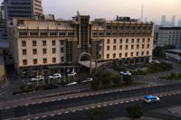 The Mövenpick Hotel & Apartments Bur Dubai is seen with the Burj Khalifa, the world's tallest building, behind it in the distance in Dubai, United Arab Emirates, Friday, Aug. 6, 2021. Some foreign contractors who powered the logistics of America's forever war in Afghanistan have now found themselves stranded on an unending layover in Dubai at the Mövenpick without a way to get home. (AP Photo/Jon Gambrell)
