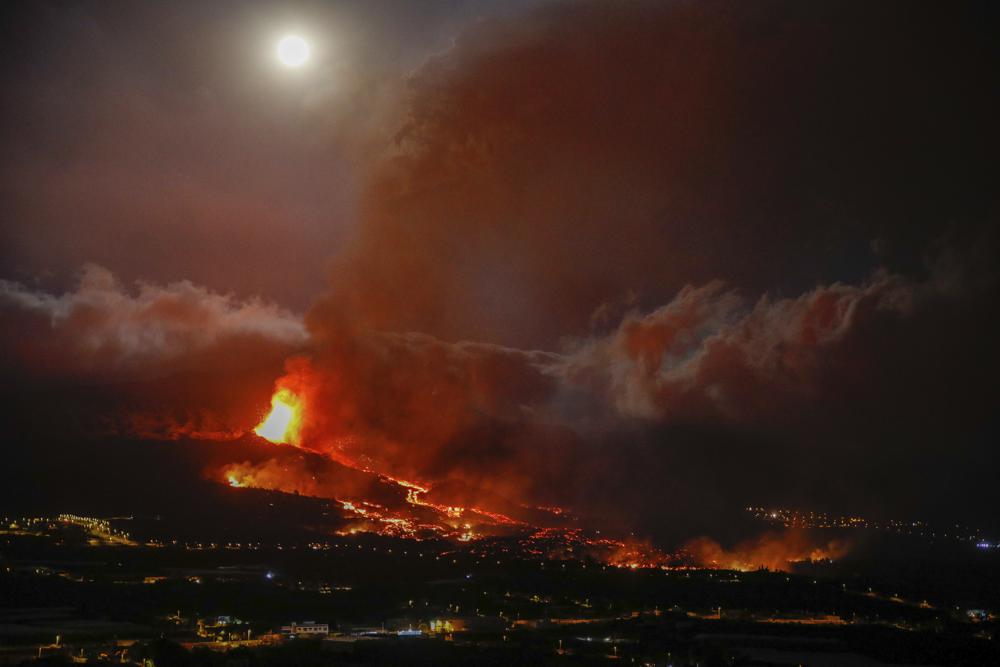 La lava entra en erupción de un volcán cerca de El Paso en la isla de La Palma en las Canarias, España, el lunes 20 de septiembre de 2021. Ríos de lava gigantes caen lenta pero implacablemente hacia el mar después de que un volcán, visto en segundo plano, hizo erupción en un Isla española frente al noroeste de África.  La lava está destruyendo todo a su paso, pero las evacuaciones rápidas ayudaron a evitar víctimas después de la erupción del domingo.  (Kike Rincon, Europa Press vía AP)