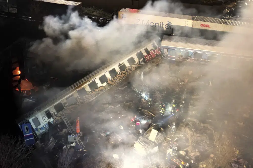 Smoke rises from trains as firefighters and rescuers operate after a collision near Larissa city, Greece, early Wednesday, March 1, 2023. The collision between a freight and passenger train occurred near Tempe, some 380 kilometers (235 miles) north of Athens, and resulted in the derailment of several train cars. (AP Photo/Vaggelis Kousioras)