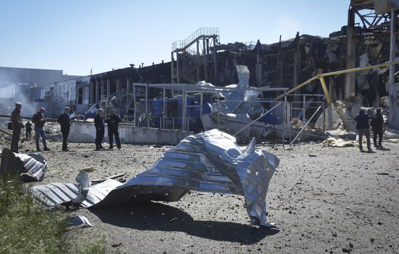 People stand near a destroyed building on the outskirts of Odesa, Ukraine, Tuesday, May 10, 2022. The Ukrainian military said Russian forces fired seven missiles a day earlier from the air at the crucial Black Sea port of Odesa, hitting a shopping center and a warehouse. (AP Photo/Max Pshybyshevsky)