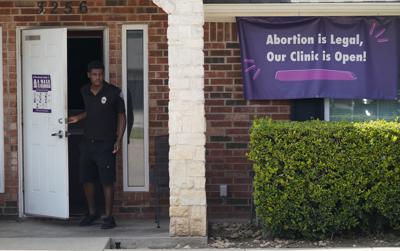 ARCHIVO - En esta fotografía de archivo del miércoles 1 de septiembre de 2021, un guardia de seguridad abre la puerta de la Clínica de Salud Whole Women en Fort Worth, Texas. El letrero dice: "¡El aborto es legal, nuestra clínica está abierta!" (AP Foto/LM Otero, archivo)
