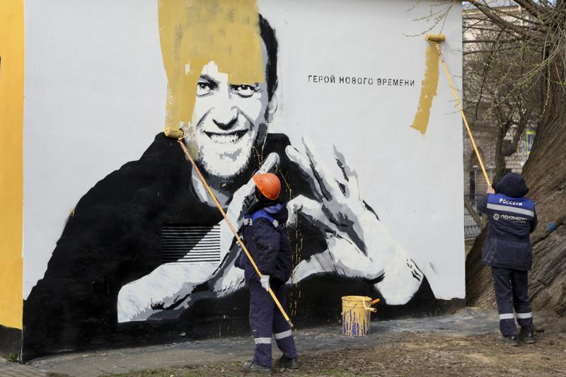 FILE - In this April 28, 2021, file photo, municipal workers paint over an image of Russia's imprisoned opposition leader Alexei Navalny in St. Petersburg, Russia. In the months before the Sept. 19 parliamentary election in Russia, authorities unleashed an unprecedented crackdown on the opposition, making sure the best-known and loudest Kremlin critics didn’t run. Navalny, Putin's biggest critic who dented United Russia's dominance in regional legislatures in recent years, is serving a 2½-year prison sentence for violating parole for a conviction he says was politically motivated. (AP Photo/Valentin Egorshin, File)