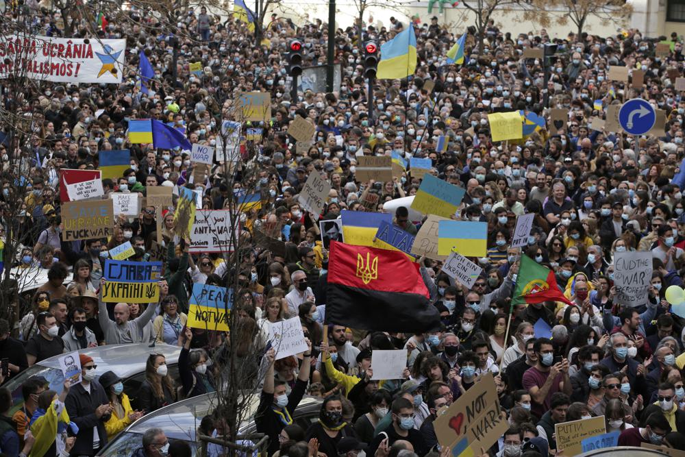 Người biểu tình cầm biển báo và vẫy cờ trong cuộc biểu tình chống lại sự xâm lược của Nga và đoàn kết với người dân Ukraine, bên ngoài đại sứ quán Nga ở Lisbon, Chủ nhật, ngày 27 tháng 2 năm 2022. Cuộc biểu tình quy tụ hàng nghìn người được gọi bởi bảy trong số các chính trị gia Bồ Đào Nha chính các đảng phái trên toàn bộ chính trị. (Ảnh AP / Ana Brigida)