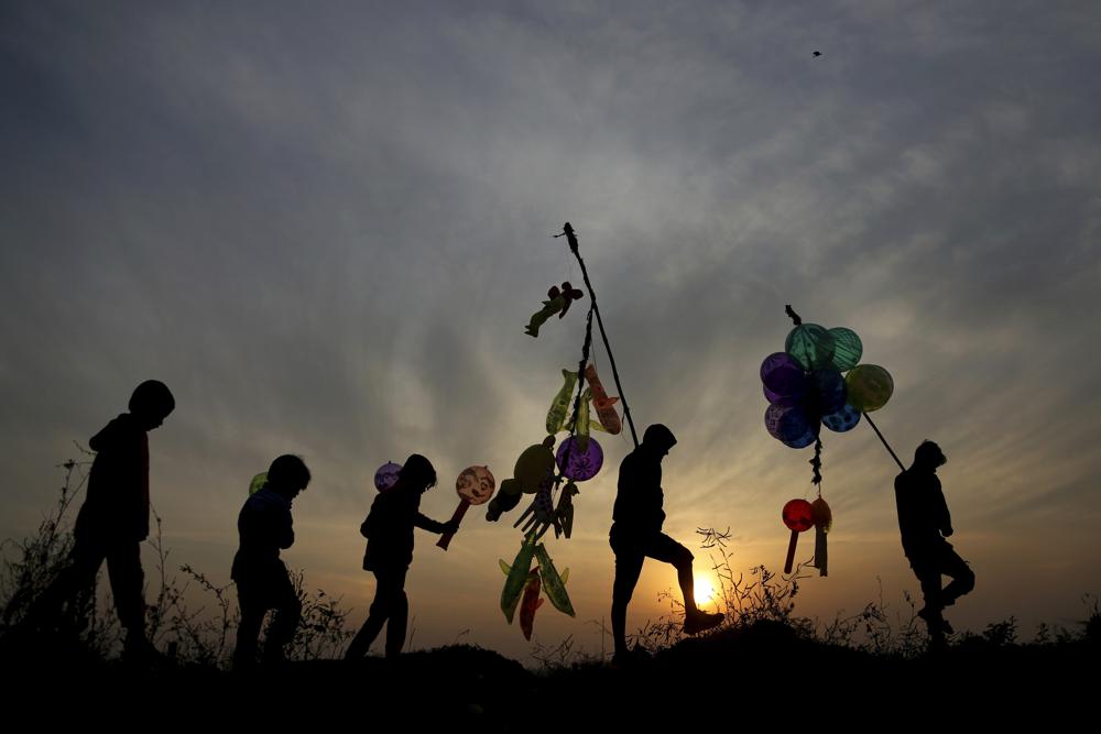 Los vendedores de globos indios caminan de regreso a casa mientras se pone el sol en la víspera de Año Nuevo en Jammu, India, el viernes 31 de diciembre de 2021 (AP Photo / Channi Anand).