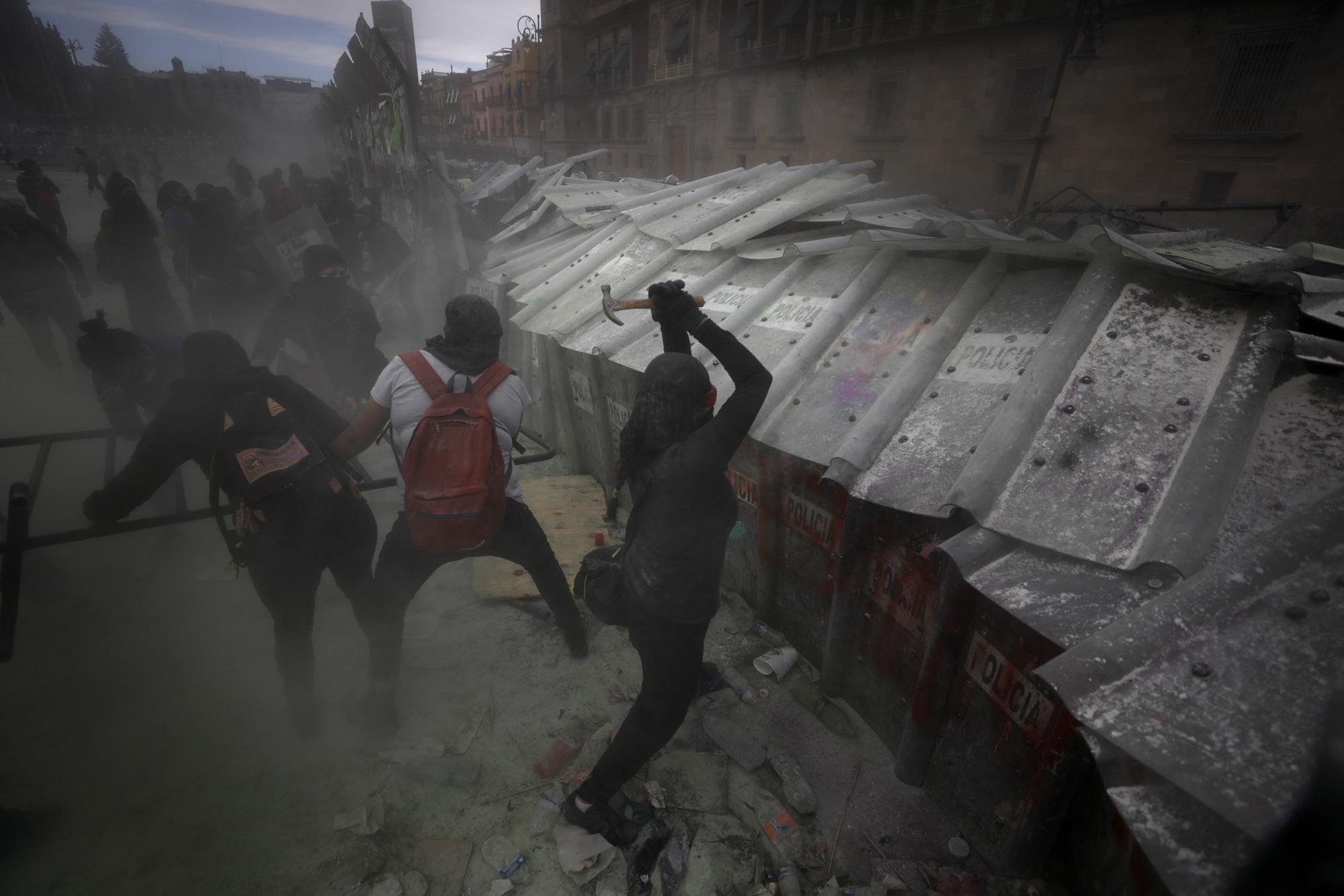 Demonstrators attack a barricade protecting Mexico City's National Palace during a march to commemorate International Women's Day and protest against gender violence, on March 8, 2021. (AP Photo/Rebecca Blackwell)