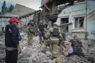 Rescatistas y residentes retiran un cadáver de debajo de los escombros de un edificio tras un ataque aéreo ruso sobre Lysychansk, en la región de Luhansk, Ucrania, el 16 de junio de 2022. (AP Foto/Efrem Lukatsky)