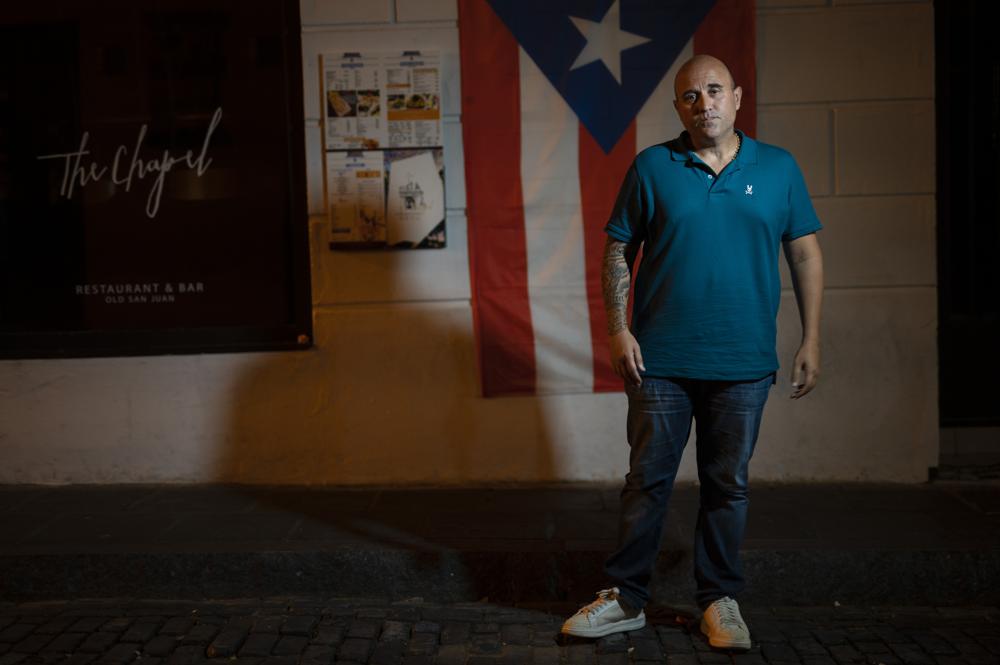 Jose Irizarry, a once-standout DEA agent sentenced to more than 12 years in federal prison for conspiring to launder money with a Colombian cartel, stands for a portrait during an interview the night before going to a federal detention center, in San Juan, Puerto Rico, Wednesday, Jan. 5, 2022. Irizarry’s downfall was as sudden as it was inevitable — the outgrowth of a lavish lifestyle that raised too many eyebrows, even among colleagues willing to bend the rules themselves. (AP Photo/Carlos Giusti)