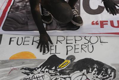 Un manifestante camina sobre una pancarta con la leyenda "Fuera Repsol del Perú", durante una protesta contra Repsol, el lunes 31 de enero de 2022, en Lima. (AP Foto/Martin Mejia)