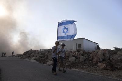 Jóvenes israelíes portan banderas en el puesto de avanzada cerca del pueblo de Nablus, en el norte de Cisjordania, el lunes 21 de junio de 2021. (AP Foto/Sebastian Scheiner)