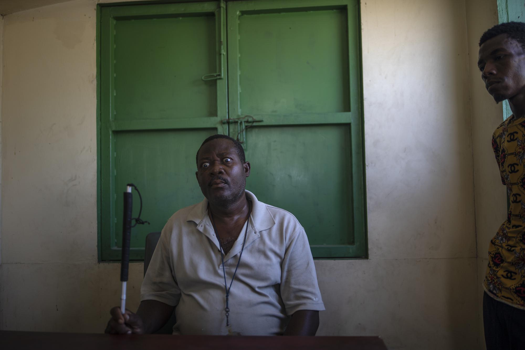 Leader La Piste's displaced residents, Joseph Dieu Faite, who is visually impaired, recalls the assault lead by police in June, at a shelter for the internally displaced in Port-au-Prince, Haiti, Friday, Sept. 17, 2021. "There were some gangsters there, I have to acknowledge that, but the police did not ask, did not say a word, did not make a difference, just evicted us and then took matches and gasoline and burned our houses one by one," Faite said. (AP Photo/Rodrigo Abd)