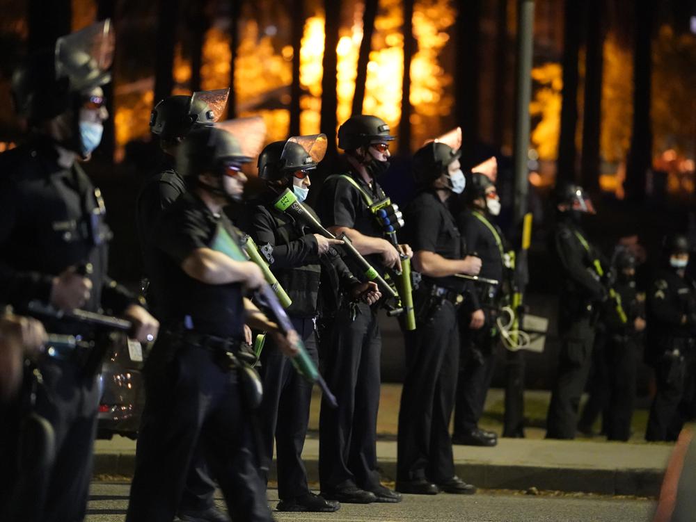 FILE - This March 24, 2021, file photo, Los Angeles police officers move in to arrest demonstrators in the Echo Park Lake homeless encampment in Los Angeles. California will project journalists from interference by police while covering civil protests under a bill signed into law Saturday, Oct. 9, by Gov. Gavin Newsom. It was the second new law within days with free speech implications. (AP Photo/Damian Dovarganes, File)