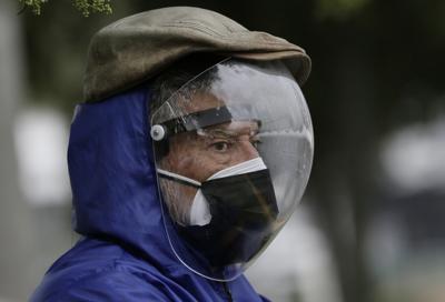 Un hombre vestido con un protector facial completo y una máscara doble para evitar el contagio de COVID-19 espera su turno para ser vacunado en Quito, Ecuador, el jueves 6 de mayo de 2021. (AP Foto/Dolores Ochoa)
