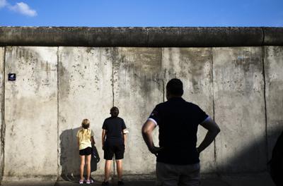 Visitantes contemplan los restos del Muro de Berlín en el monumento en la Bernauer Strasse en vísperas del 60 aniversario del inicio de la construcción, 12 de agosto de 2021. El 13 de agosto de 1961, el gobierno alemán oriental inició la construcción del muro para separar a Berlín en sectores oriental y occidental, un nuevo paso en la Guerra Fría entre la alianza occidental y el blique comunista del este. (AP Foto/Markus Schreiber)