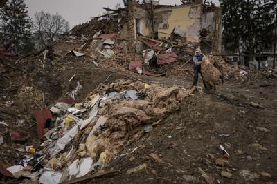 Un hombre retira escombros de edificios destruidos durante combates entre las fuerzas rusas y ucranianas, colocándolos en un cráter provocado por una explosión, el viernes 1 de abril de 2022, en las afueras de Kiev, Ucrania. (AP Foto/Vadim Ghirda)