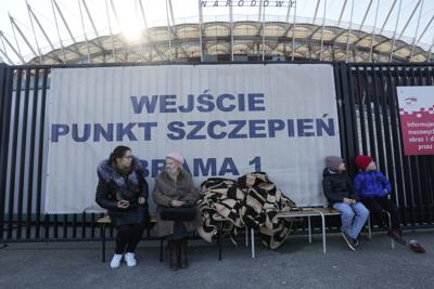 Refugiados ucranianos están sentados afuera de una banca cerca de un punto de solicitud especial en el Estadio Nacional en Varsovia, Polonia, el sábado 19 de marzo de 2022. (AP Foto/Czarek Sokolowski)