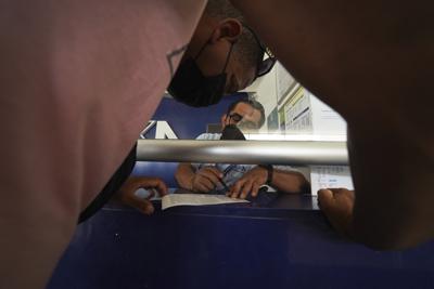 Migrantes compran boletos de autobús luego de recibir documentos que les permiten viajar legalmente por México, en Huixtla, estado de Chiapas, México, el viernes 10 de junio de 2022. Miles de migrantes salieron a pie de Tapachula a principios de semana, cansados de esperar que se normalice su estatus en una región con poco trabajo, con el objetivo final de llegar a Estados Unidos. (Foto AP/Marco Ugarte)