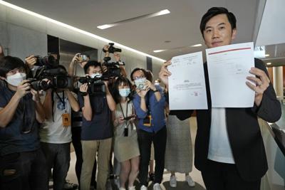 El legislador Cheng Chung-Tai, rodeado por periodistas, muestra un documento, luego de su descalificación de la legislatura de Hong Kong, jueves 26 de agosto de 2021. (AP Foto/Vincent Yu)