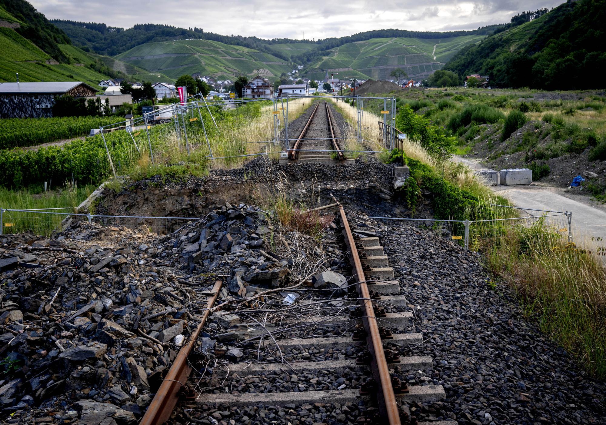 Debris from last year's floods lie on a destroyed railway line in the village of Dernau in the Ahrtal valley, Germany, Tuesday, July 6, 2022. Flooding caused by heavy rain hit the region on July 14, 2021, causing the death of about 130 people. (AP Photo/Michael Probst)