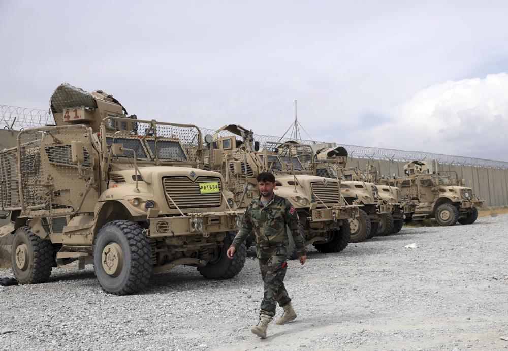 Солдат афганской армии проходит мимо автомобилей с защитой от мин и засад MRAP, которые остались после того, как американские военные покинули авиабазу Баграм, в провинции Парван к северу от Кабула, Афганистан, в понедельник, 5 июля 2021 г. США покинули афганский аэродром Баграм после того, как почти 20 лет, завершая свою «вечную войну» в ночи, не уведомив нового афганского командующего до тех пор, пока не прошло более двух часов после того, как они ускользнули.  (AP Photo / Rahmat Gul)