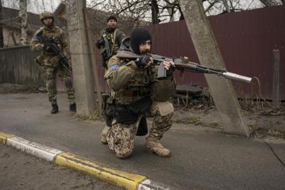Un soldado ucraniano cubre la retirada de otros soldados que revisan cadáveres tirados en las calles en el suburbio Bucha, en Kiev Ucrania, el sábado 2 de abril de 2022. (AP Foto/Vadim Ghirda)