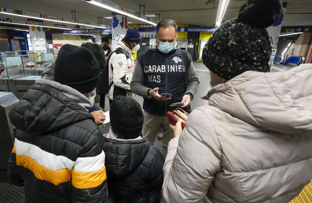 A Carabinieri policeman checks the green health pass of public transportation passengers in Rome, Monday, Dec. 6, 2021, on the first day a super green health pass went into effect. Italian police can check whether diners in restaurants or bars have a "super" green health pass certifying that they are either vaccinated or have recently recovered from the virus. (AP Photo/Andrew Medichini)