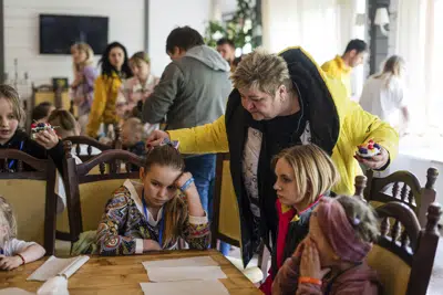 Nina Poliakova, de pie, habla con su hija adoptiva Olha Hinkina en el campo de recuperación para niños y sus madres afectados por la guerra cerca de Leópolis, Ucrania, el miércoles 3 de mayo de 2023. Una generación de niños ucranianos ha visto sus vidas trastornadas por la invasión rusa a su país. La guerra los ha sometido a bombardeos constantes, ha desarraigado a millones de sus hogares y ha dejado huérfanos a muchos. Cientos de niños han muerto por la guerra. (AP Foto/Hanna Arhirova)