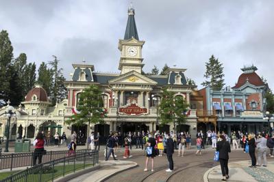 Turistas aguardan para entrar a Disneylandia París en Marne-la-Vallée, al este de París, jueves 17 de junio de 2021. El sector turístico francés da un paso más hacia la recuperación pospandemia con la reapertura de Disneylandia Paris, dos semanas después de que el país reabrió formalmente sus fronteras al turismo extranjero. (AP Foto/Catherine Gaschka)