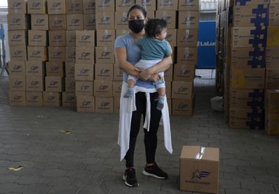 ARCHIVE - Una mujer con su hijo en brazos al lado de un kit de alimentos donados por el gobierno municipal después de haber recibido la vacuna contra COVID-19 de Sinovac en Guayaquil, Ecuador, el 22 de julio de 2021. Según el la delegación en Ecuador del Fondo de las Naciones Unidas para la Infancia, la mitad de los hogares con niños en Ecuador tiene dificultad para acceder a alimentos como consecuencia de la pandemia, según un informe presentado el 10 de noviembre de 2022, con ocasión del Día Mundial de la Infancia. (AP Foto/Dolores Ochoa, Archive)