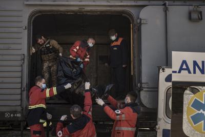 Un militar ucraniano y rescatistas cargan el cadáver de un soldado ruso en un tren refrigerado en Járkiv, Ucrania, el jueves 5 de mayo de 2022. (AP Foto/Felipe Dana)