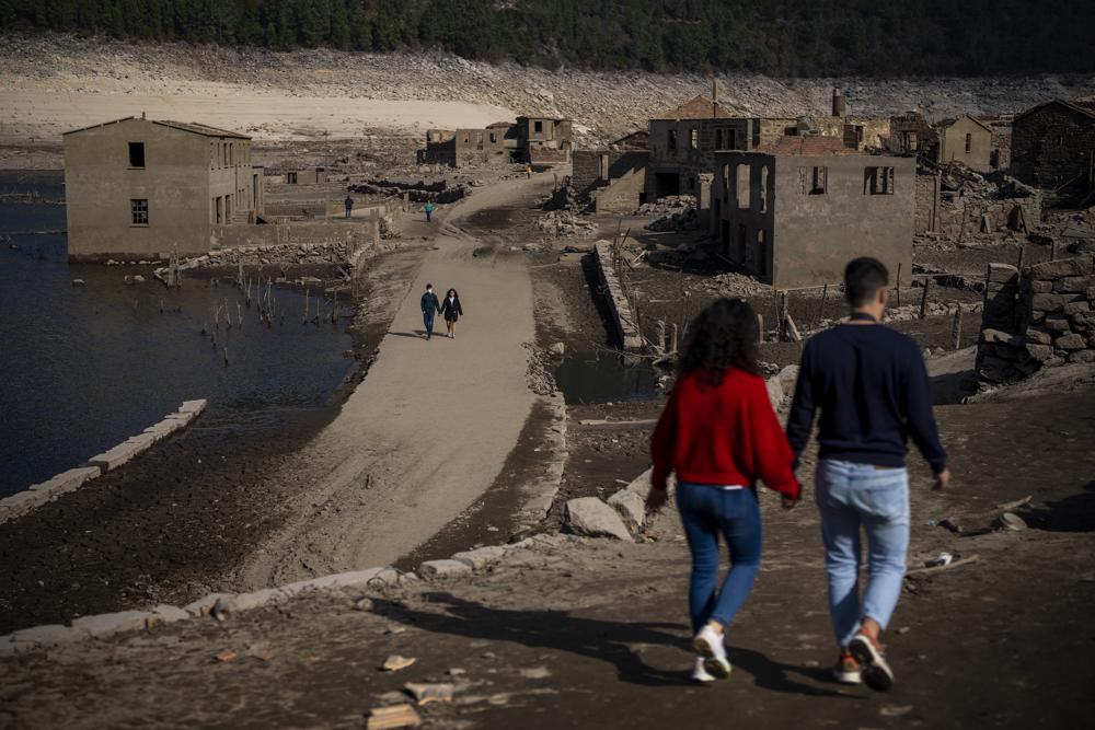 Visitantes caminando por el antiguo pueblo de Aceredo, reaparecido debido a la sequía en el embalse de Lindoso, en el noroeste de España, el viernes 11 de febrero de 2022.  Gran parte de España sufre una sequía extrema o prolongada, tras un invierno en el que ha llovido apenas un tercio de la media de los últimos años. La situación es similar en la vecina Portugal, donde el 45% del país sufre una sequía "grave" o "extrema". (AP Foto/Emilio Morenatti)