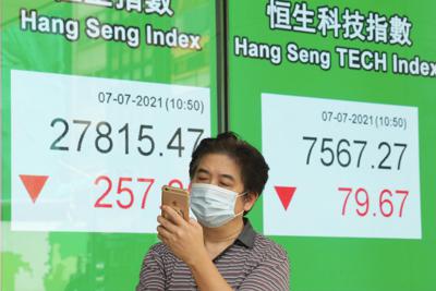 Una persona frente a una  cartelera financiera en Hong Kong el 7 de julio del 2021.  (Foto AP/Kin Cheung)